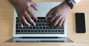 Close-up of man's hands typing on laptop computer.