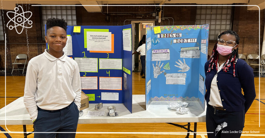 Two Alain Locke all-stars stand before their projects in the gymnasium at the 2022-23 K-8 Alain Locke Science Fair.